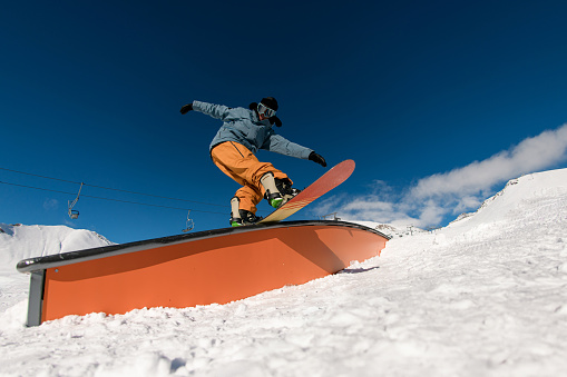Demonstrating finesse, the snowboarder engages in wallride stunts, combining skillful tricks with precise balance on the snowy slope.
