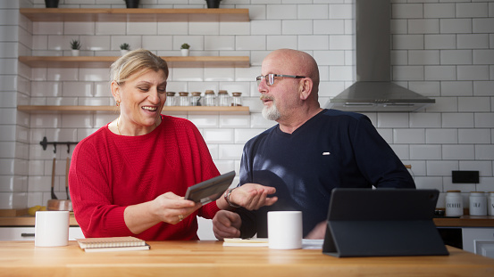 Retired couple sit in kitchen doing paperwork, checking calculating bills bank loan payment, discuss unpaid debt taxes. Old grandparents family money problem concept