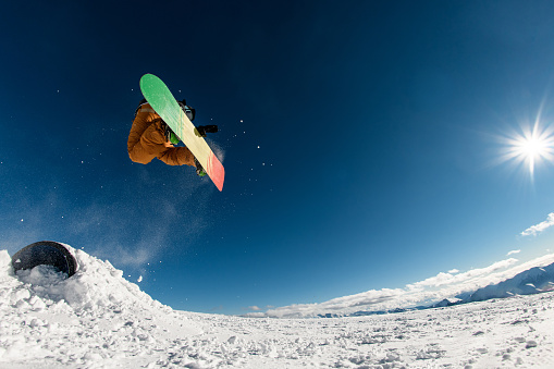 Experience the excitement as the snowboarder achieves impressive altitude, executing a high jump with the dynamic assistance of the springboard.