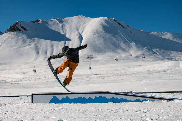 istock Seated snowboard trick: rider skillfully balances on wallride with finesse. 2113198904