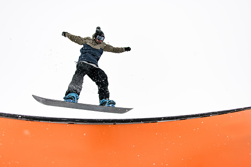 pro snowboard rider leaps into a wallride, conquering slope challenges with remarkable skill.