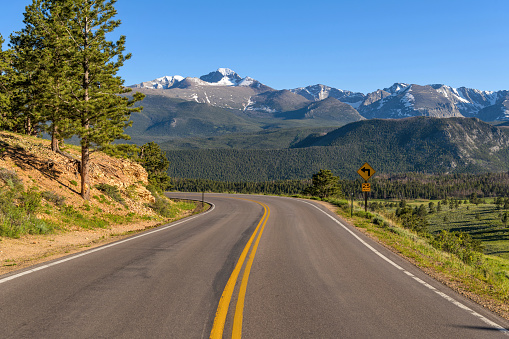A Spring evening view of winding Highway 36, with snow-capped Longs Peak towering in background, in Rocky Mountain National Park, Colorado, USA.
