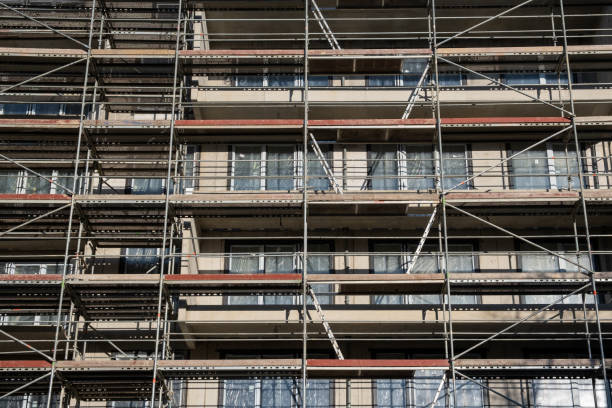 facade wall on a construction site in europe, scaffolding among windows. unfinished modern apartment architecture building site. - progress working incomplete continuity ストックフォトと画像