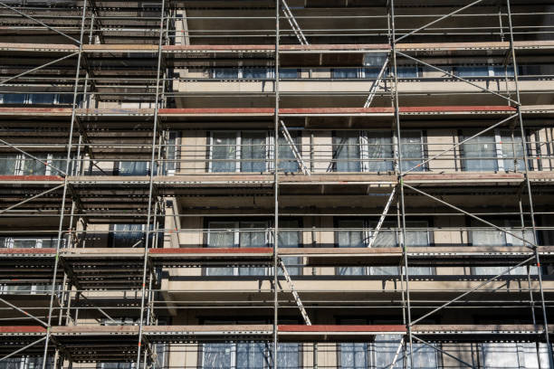 facade wall on a construction site in europe, scaffolding among windows. unfinished modern apartment architecture building site. - progress working incomplete continuity - fotografias e filmes do acervo