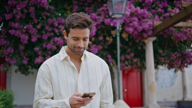 istock Relaxed gentleman strolling blossom alley closeup. Happy guy reading message 2113312112