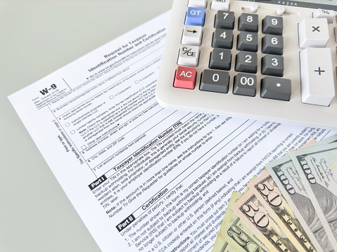 Tax forms and dollar bills with calculator on table top