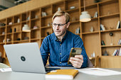 A man efficiently manages emails and communicates from his desk in the office