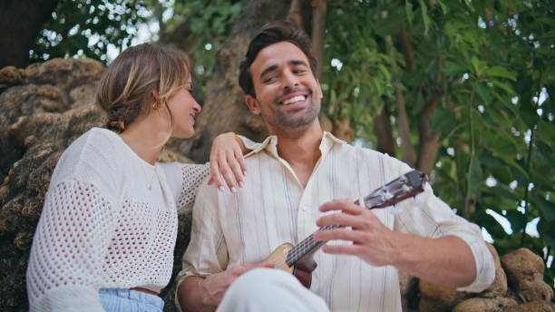 istock Handsome man playing serenade ukulele relaxing girlfriend on weekend closeup 2113378179