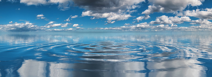 Cumulus clouds reflected on undulations in the ocean