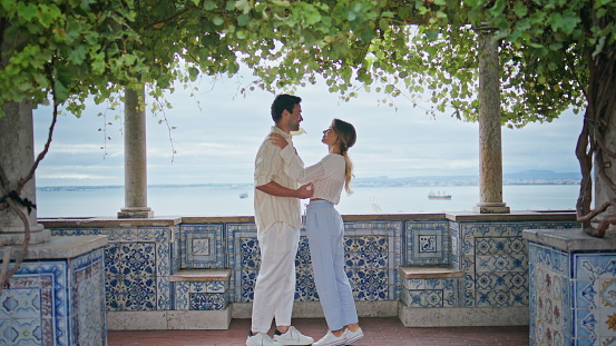 Happy couple kissing date on seascape terrace zoom on. Affectionate man woman embracing each other meeting at mediterranean city. Young romantic lovers feeling joy bonding at marine view balcony