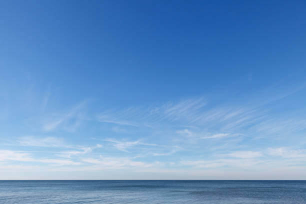 Beautiful blue sky over the sea with translucent, white, Cirrus clouds. The horizon line