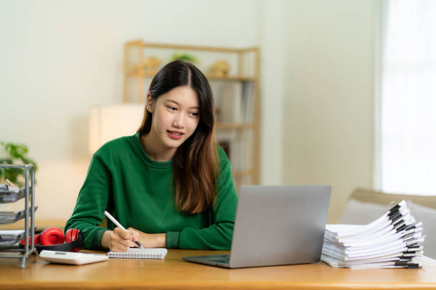 istock Ambitious Asian girl working from home Looking at laptop screen and smiling, checking mail or doing research while working remotely, online startup business, telemarketing 2113472771