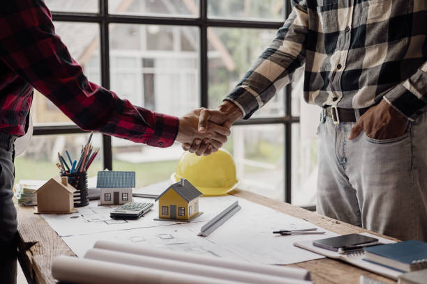 istock Close-up photo of architect and construction engineer holding hands while working for teamwork and cooperation concept after completing agreement in office construction site with house plans on table 2113493367