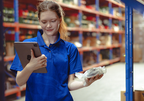 Distribution warehouse worker using digital tablet inspecting inventory stock on shelf. Female store supervisor or logistic engineer working at storage room in storehouse. Goods delivering management