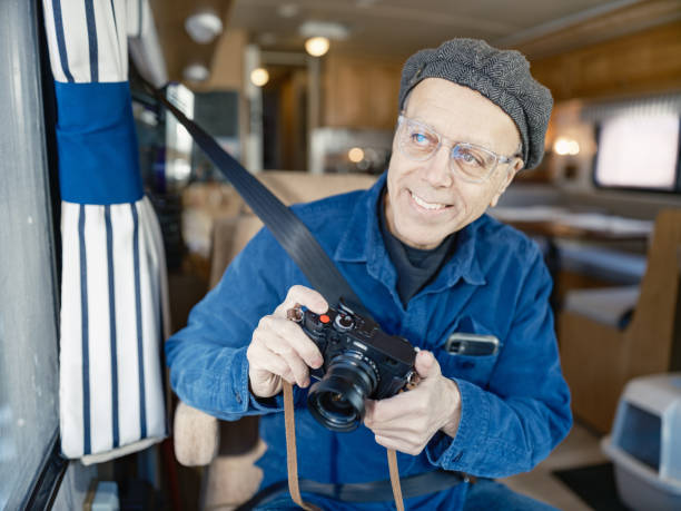 Senior man enjoying RV trip adventure. He is dressed in casual clothing. Interior of  recreational vehicle during the day in Ontario, Canada.
