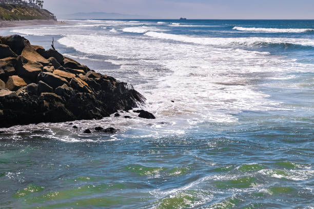 Waves crash upon the rocky shoreline in Carlsbad California