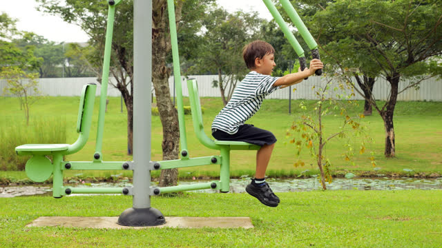 Boy diligently try to exercise on chest press machine at park gym
