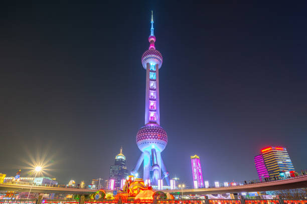 Shanghai, China - March 16th 2024: Busy traffic road with The Oriental Pearl Tower at night. The Oriental Pearl Tower is a TV tower in Shanghai, China. It's very famous. It's very iconic.