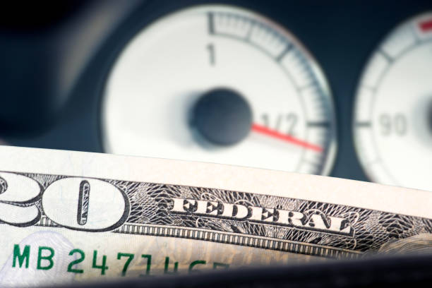 istock Dollar bills and fuel gauge in a car 2113744200