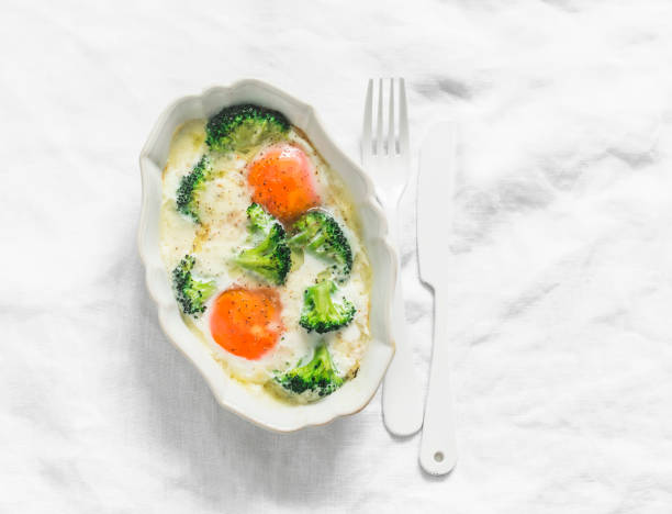 Delicious breakfast, brunch - baked eggs with broccoli and mozzarella on a light background, top view