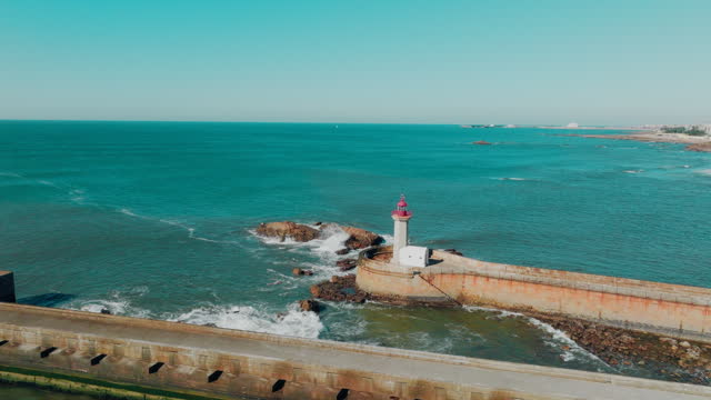 Drone view of Lighthouse Felgueirasin Porto with waves and cityscape, sunny day