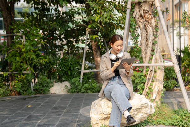 istock Businesswoman using a digital tablet while sitting at public park 2113848589