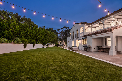 A patio with lawn chairs and a fence decorated with lights