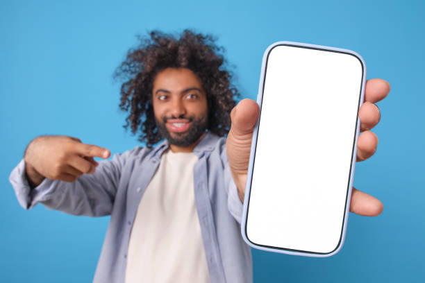 istock Young smiling Arabian man with phone in hand points finger at white display 2113887173