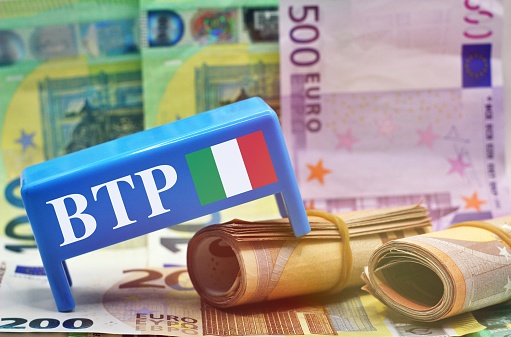 Table with european banknotes as background with the text BTP translating as Italian government bonds.