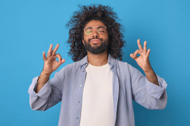Young smiling Arabian man with beard takes pose from yoga stands in studio