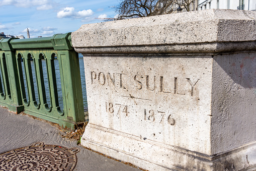 Paris, France - March 26, 2024: Inscription on a stone of the parapet of the Sully bridge with the dates of construction. The Sully bridge (aka Pont de Sully) is a bridge crossing the Seine river