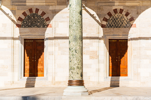 Camera focused on a column with two windows and dramatic lighting and shadows on the wall in an historical mosque.