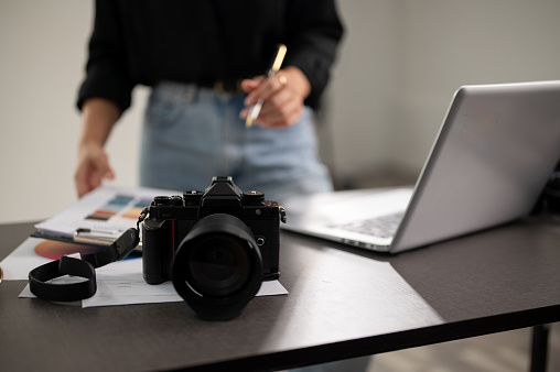 A close-up shot of a professional DSLR camera on a desk in a photoshoot studio. a female photographer working in a studio. selective focus