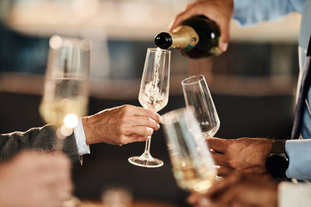 Pouring champagne at office party! Close up of unrecognizable businessman pouring champagne to his colleagues on a party in the office. champagne stock pictures, royalty-free photos & images