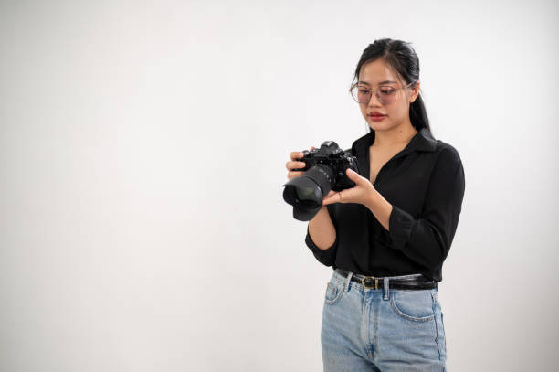 istock A confident, experienced Asian female photographer is adjusting her DSLR camera, preparing photoshoot equipment, and working in the studio. 2114050710