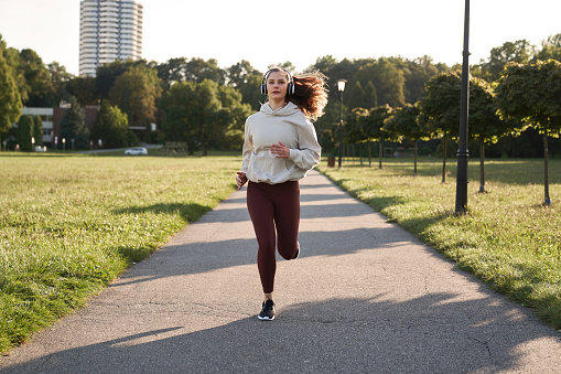 Wide shot of woman jogging in the park during sunset