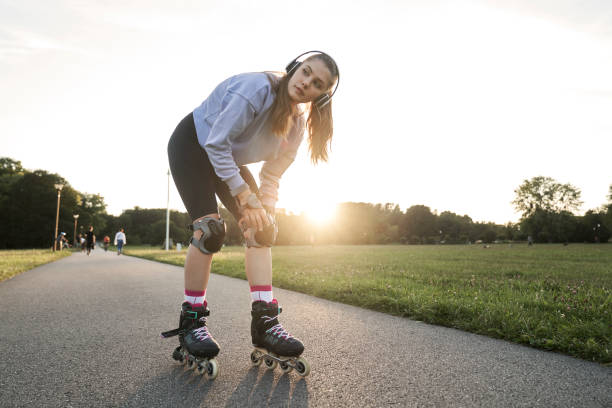 istock Young woman getting ready for  rollerblading in the park 2114089522