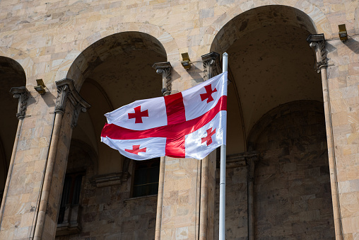Red crosses on a white background of the national flag of the Republic of Georgia, atop a flagpole, blowing in the wind in Tbilisi.
