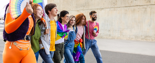 LGBTI community group of people having fun walking together hugging each other outdoors showing unity.