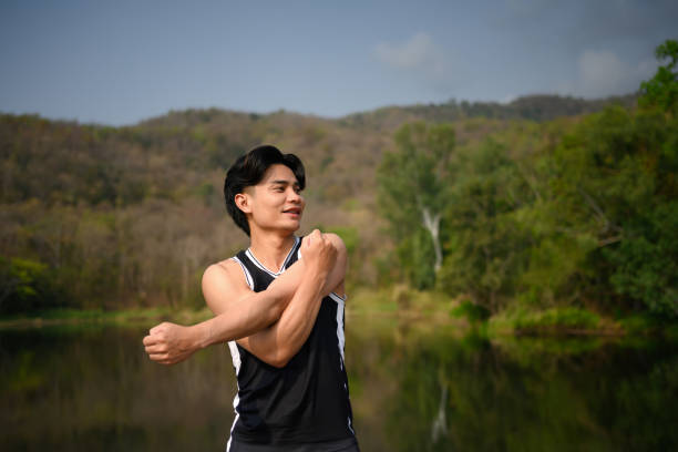 Sporty man doing stretching exercises preparing for morning workout in the park.