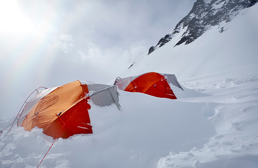 Two tents in camp covered in snow on Denali during a sunny day