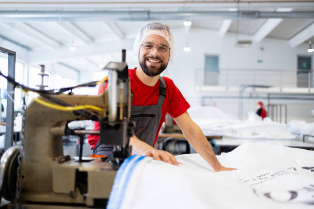 istock Portrait of professional tailor working on sewing machine inside textile factory. 2114202176