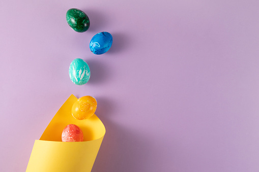 Painted easter eggs with papers on purple background