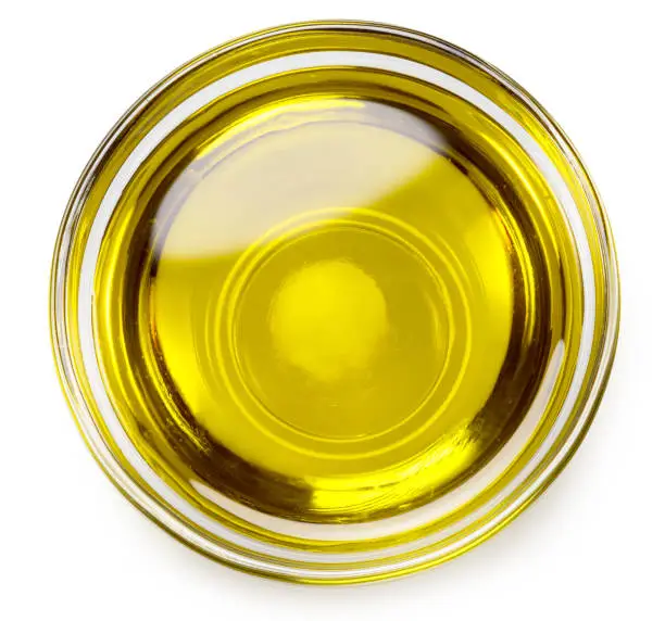 Photo of Glass bowl of olive oil on white background, top view.. File contains clipping path.