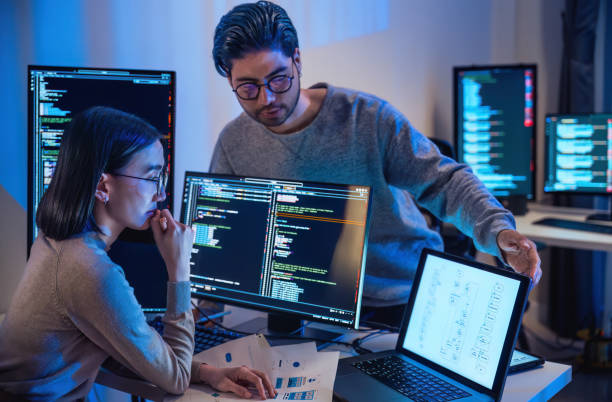 азиатская и индийская команда разработчиков devops обсуждают кодирование promgram с программным компьютером ночью в офисе - компьютерное программное обеспечение стоковые фото и изображения