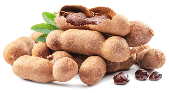 Ripe tamarind fruit, leaves and some tamarind seeds isolated on white background.