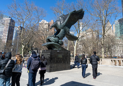 Battery Park, Manhattan, New York, USA - March, 2024. Tourists near the Bald eagle statue, by Albino Manca, part of the East Coast Memorial.