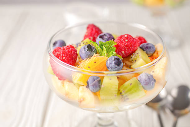 Delicious dietary fresh fruit salad on a light wooden table background