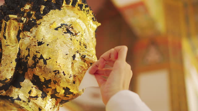 Applying a gold leaf to the face of Buddha Image