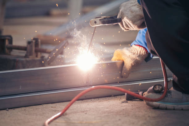 istock Construction Worker hands using Welding machinery iron metal sparking. Men hands wear protective glove Hot flame metal work cutting fire iron workshop. Locksmith use Welding machine cut metal process 2114345245